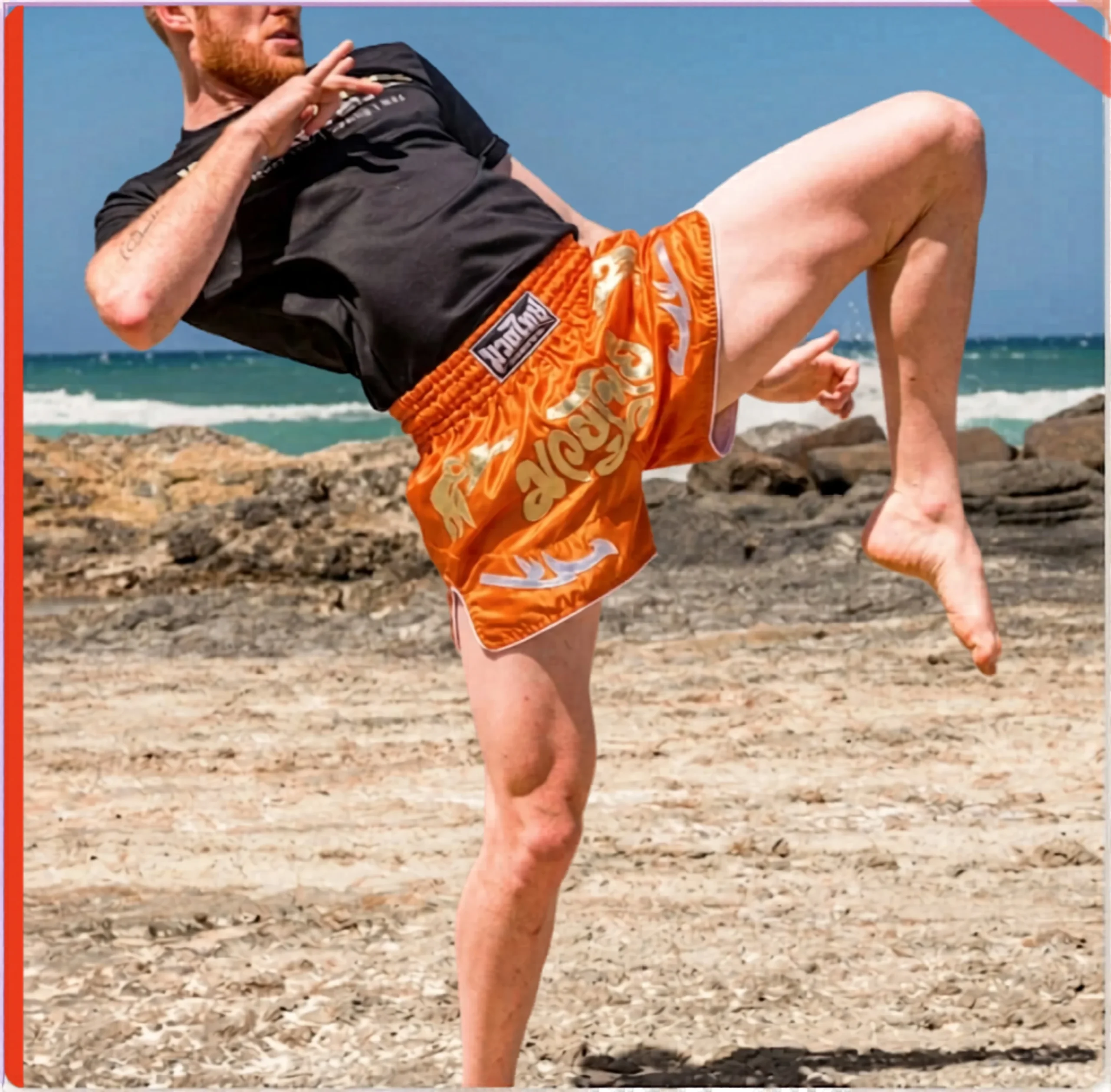 A Muay Thai fighter executes a high left roundhouse kick on a beach, wearing orange and silver custom shorts.