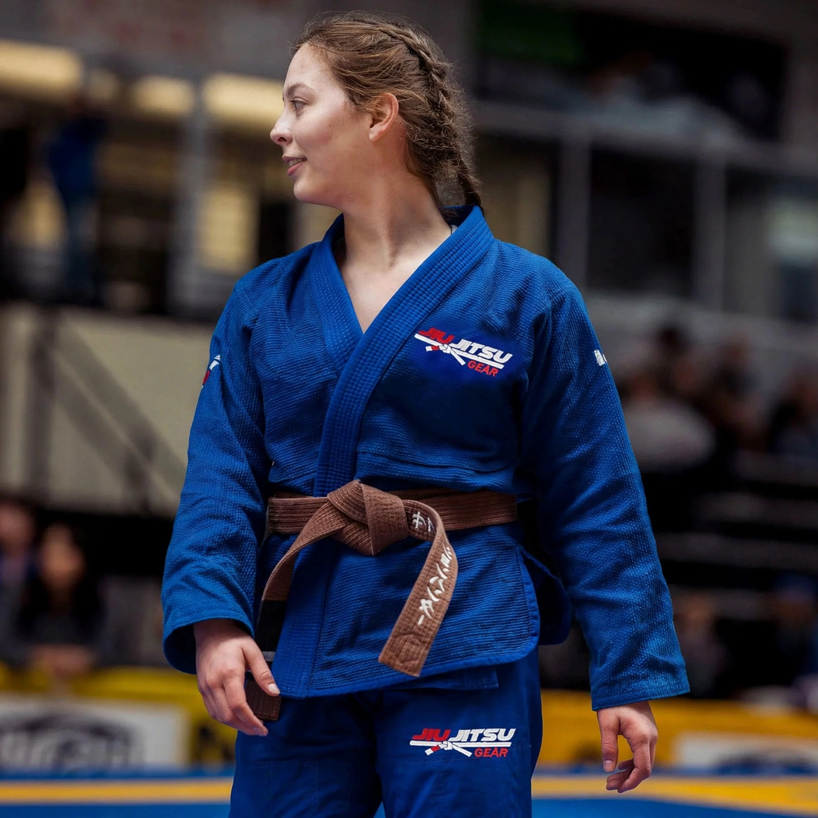Female BJJ brown belt athlete wearing royal blue Brazilian Jiu Jitsu Gi set - JIU JITSU GEAR pearl weave kimono jacket and pants with embroidered logo on chest and thigh